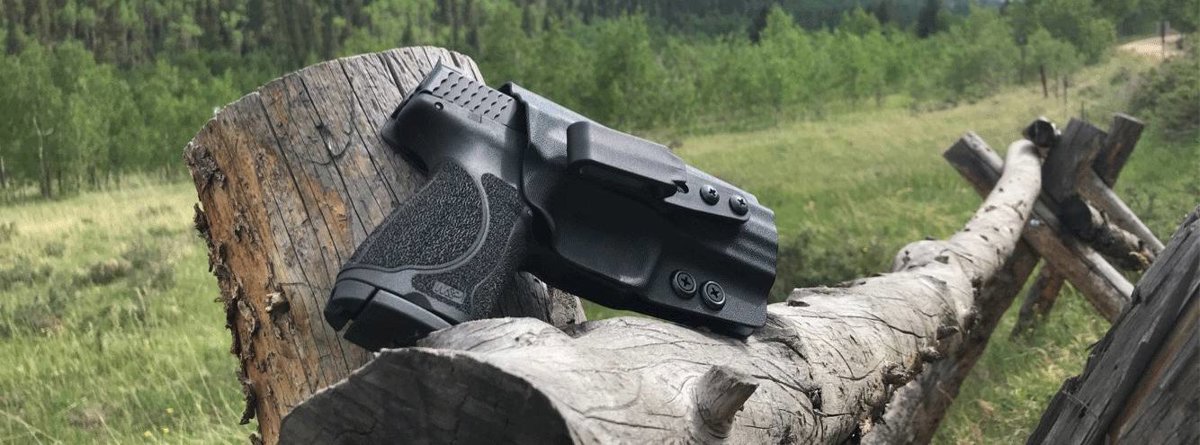 A holstered pistol at a fence line in open hunting country